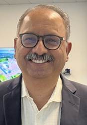 A person with glasses smiling

Description automatically generated